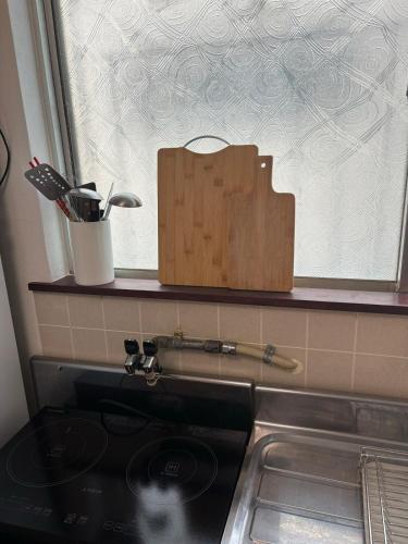 a kitchen counter with a stove and a cutting board at A cozy home between Osaka and Kyoto -UNiCO- in Takatuki