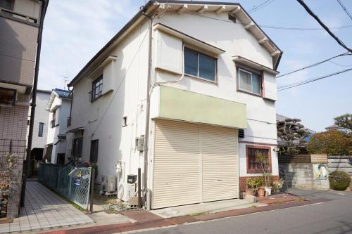 a white house with a large garage at A cozy home between Osaka and Kyoto -UNiCO- in Takatuki