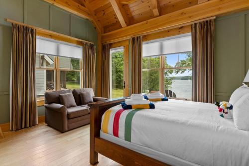 a bedroom with a bed and a chair and windows at Port Cunnington Lodge in Dwight