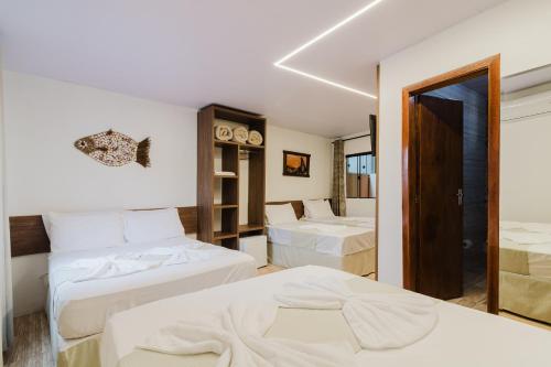 een hotelkamer met twee bedden en een spiegel bij Ancoradouro Pousada in Penha