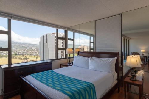 a bedroom with a bed with a large window at Waikiki Banyan Condo with Mountain Views Near Waikiki Beach, Free Parking (22113) in Honolulu