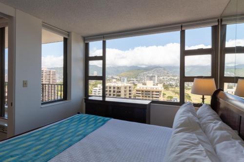 a bedroom with a bed and a large window at Waikiki Banyan Condo with Mountain Views Near Waikiki Beach, Free Parking (22113) in Honolulu
