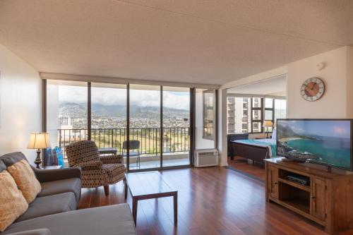 a living room with a couch and a flat screen tv at Waikiki Banyan Condo with Mountain Views Near Waikiki Beach, Free Parking (22113) in Honolulu