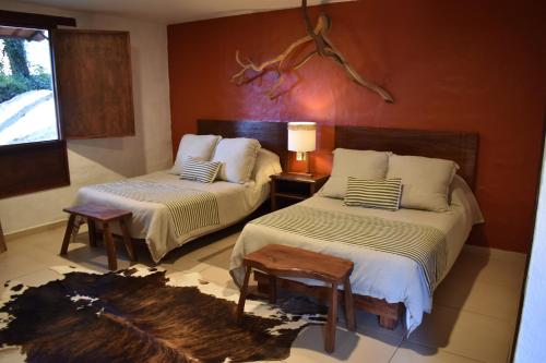 a bedroom with two beds and a table and a window at El Mesón del Ticúz Tapalpa in Tapalpa