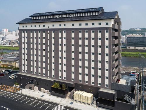 a large building with a sign on top of it at Hotel Route-Inn Tsuyama Ekimae in Tuyama