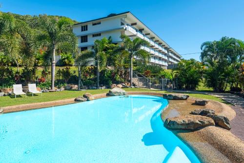a swimming pool with a resort building in the background at Lagoon Apartments on Hamilton Island by HIHA in Hamilton Island