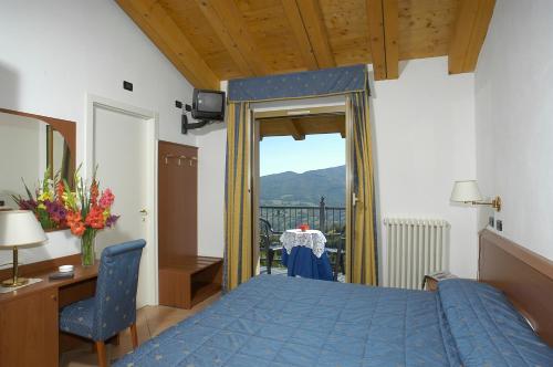 a bedroom with a blue bed and a desk and a window at Hotel Al Poggio in Sestola