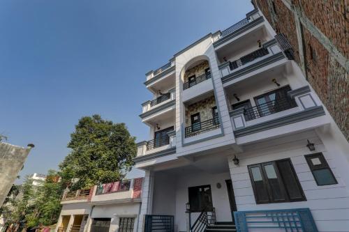 a white building with balconies and a tree at Hotel O The Lemongrass in Colonelganj
