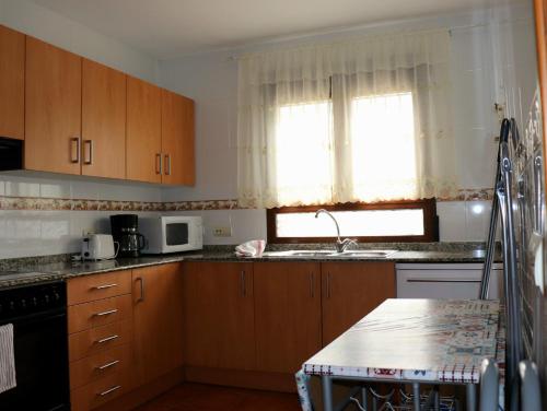 a kitchen with wooden cabinets and a sink and a window at Casa Rural Claudia in Albarracín