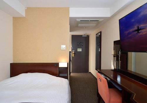 a hotel room with a bed and a flat screen tv at APA Hotel Haneda Anamori Inari Ekimae in Tokyo