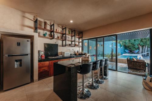 a kitchen with a refrigerator and a counter with stools at CASA YAXCHE luxury house in downtown Mérida in Mérida