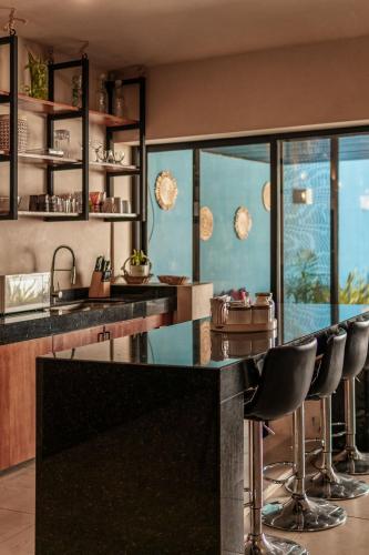a kitchen with a black counter and stools at CASA YAXCHE luxury house in downtown Mérida in Mérida