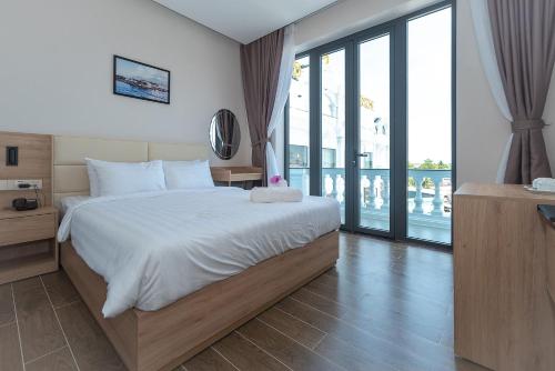 a bedroom with a large bed and a balcony at Bamboo Riverside Boutique Hotel in Ben Tre