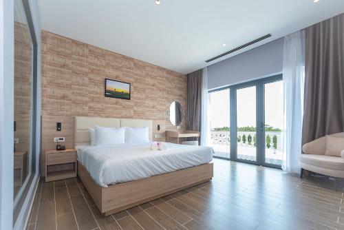a bedroom with a large bed and a balcony at Bamboo Riverside Boutique Hotel in Ben Tre