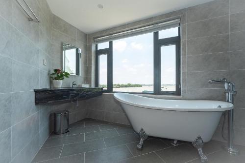 a bath tub in a bathroom with a window at Bamboo Riverside Boutique Hotel in Ben Tre