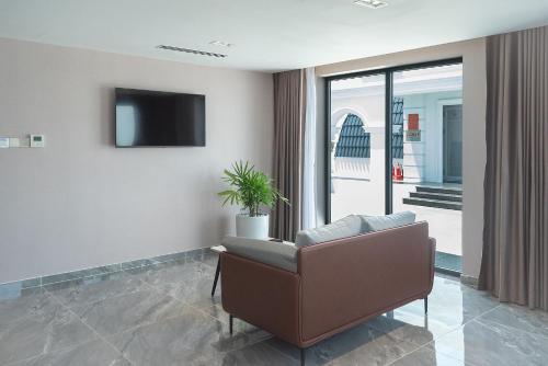 a living room with a chair and a tv at Bamboo Riverside Boutique Hotel in Ben Tre