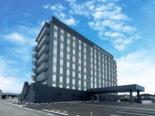 a hotel building with a parking lot in a parking lot at Hotel Route Inn Tonami Inter in Tonami