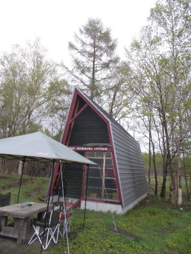 a small cabin with a picnic table and a tent at Niseko Shirokuma Cottage in Niseko