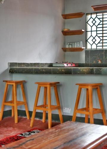 three wooden stools in a room with a counter at Ushongo Econostay in Wanga