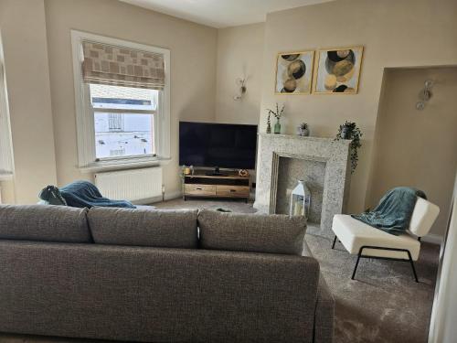 a living room with a couch and a fireplace at Fadó & Tide Apartments in Filey