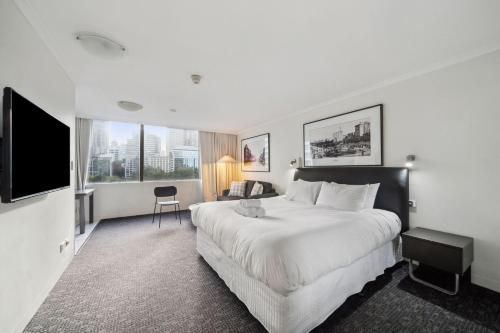 a hotel room with a large bed and a television at City Pad with Hyde Park Views, Walk to Everything! in Sydney