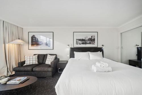 a hotel room with a large bed and a chair at City Pad with Hyde Park Views, Walk to Everything! in Sydney