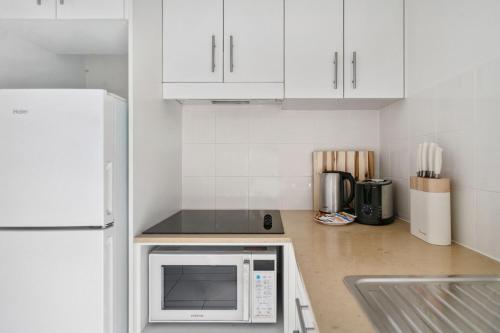 a kitchen with white cabinets and a white microwave at City Pad with Hyde Park Views, Walk to Everything! in Sydney