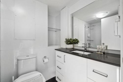 a white bathroom with a toilet and a sink at City Pad with Hyde Park Views, Walk to Everything! in Sydney