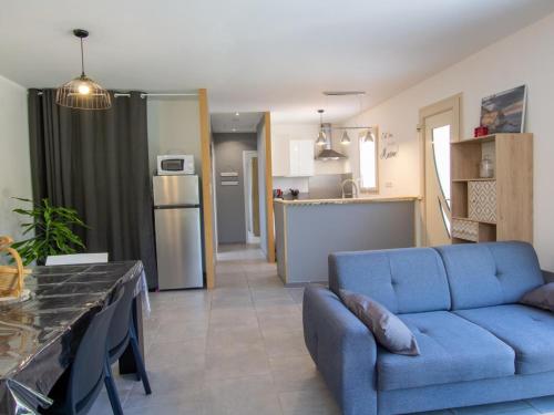 un salon avec un canapé bleu et une cuisine dans l'établissement **Gîte cosy avec terrasses et jardin à 7 km de Montignac, tout équipé, idéal pour explorer la Dordogne** - FR-1-616-202, à Auriac-du-Périgord