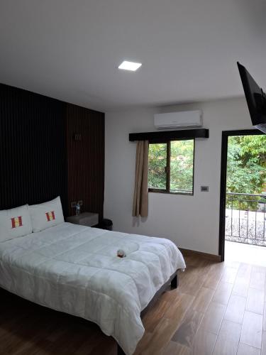 a bedroom with a large white bed and a window at Hotel Sevilla Palenque in Palenque
