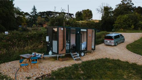 a tiny house with a van parked in a driveway at Belrose Estate by Tiny Away in Dumbalk