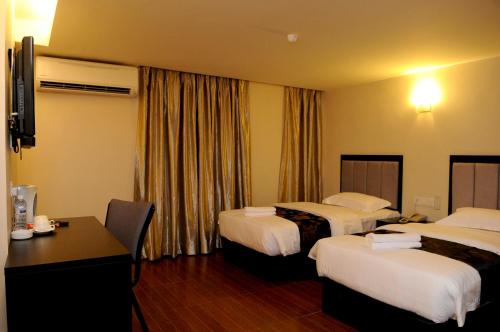 KK Waterfront Hotel في كوتا كينابالو: غرفة فندقية بسريرين ومكتب