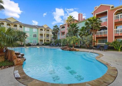 a swimming pool in a resort with palm trees and buildings at 2 Bd, Oceanfront Oasis, Lots of deals and Winter Texans book early in Galveston