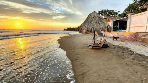 a beach with two chairs and an umbrella and the ocean at 2 Casitas for 8 guests on Beach Front w Pool & AC in Pochomil