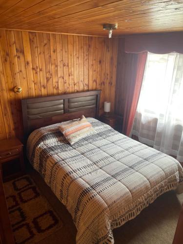 Un dormitorio con una cama con una pared de madera. en Casa Rukalma Centro, en Villarrica