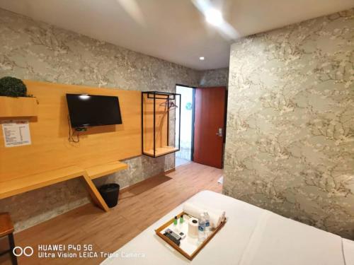 a living room with a tv on a wall at Raintree Boutique Hotel in Kajang
