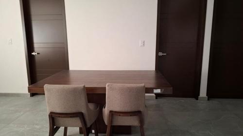 a wooden table with two chairs in a room at departamento compartido Aeropuerto-GNP in Mexico City
