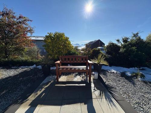 a wooden bench sitting on a sidewalk in the sun at Wayfarers Lodge in Lake Tekapo