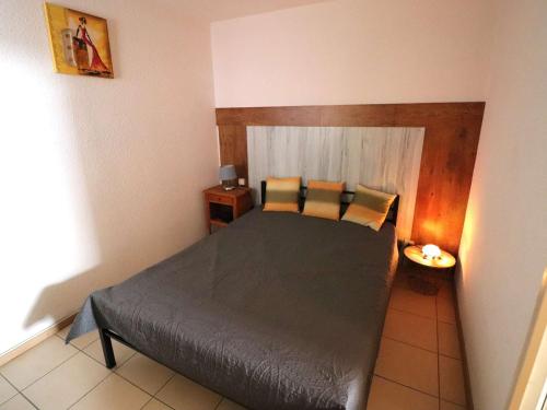 une chambre avec un lit avec une tête de lit en bois dans l'établissement Duplex Cosy avec Terrasse, Clim et Parking à deux pas des Plages - FR-1-307-285, au Grau-du-Roi