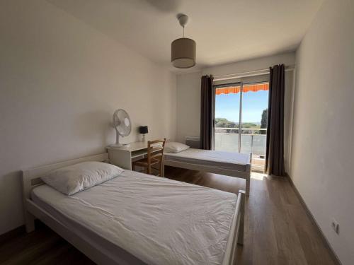 une chambre avec deux lits et un bureau et une fenêtre dans l'établissement Appartement T3 moderne avec terrasse et vue mer - Le Lavandou - FR-1-308-208, au Lavandou