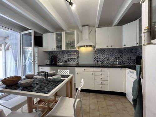 une cuisine avec des armoires blanches et une table dans l'établissement Villa T2 cabine climatisée avec parking, proche mer - FR-1-249-433, au Cap d'Agde
