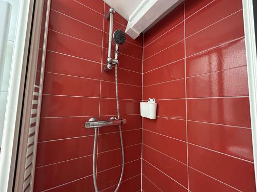d'une douche avec un mur en carrelage rouge. dans l'établissement Villa T2 cabine climatisée avec parking, proche mer - FR-1-249-433, au Cap d'Agde