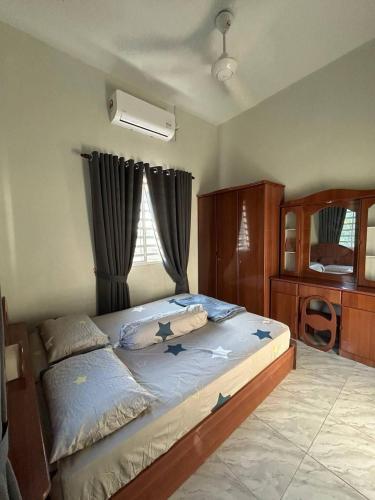 a bedroom with a large bed with blue sheets and a window at D' Bamboo Madu Homestay in Yan