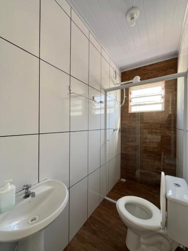 a white bathroom with a toilet and a sink at Chalé em Ubatuba para 12 pessoas com Wi-Fi in Ubatuba