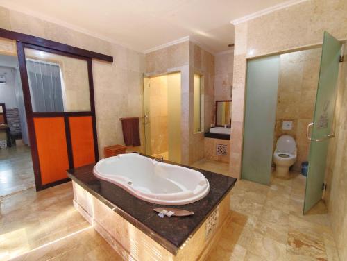 a large bathroom with a tub and a toilet at Private Pool Villas Kuta Bali in Kuta