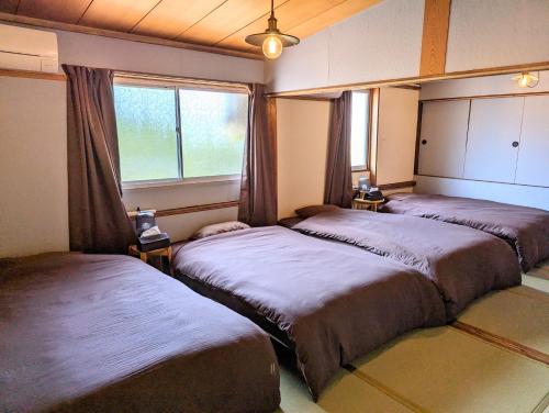 a bedroom with two beds and a window at 蔵サウナのある貸切古民家宿 ojirotomarlo in Tsuiyama