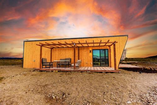 a small house with two chairs and a table on a deck at stargazing grand canyon skylight tiny home venus in Williams