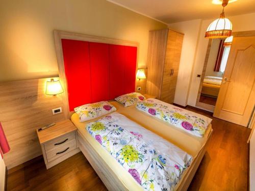 a bedroom with two beds and a red headboard at Amazing apartment house Diamant with breathtaking view in Santa Cristina in Val Gardena