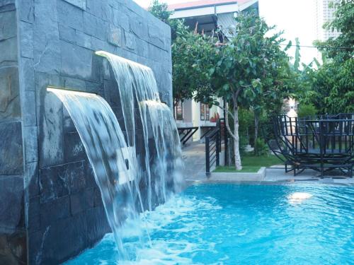 a waterfall in a pool with a stone wall at Activate C3 Hostel in Phnom Penh