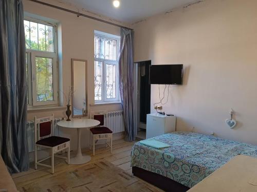 a bedroom with a bed and a table and a table at Номер в Гостевом доме у моря in Odesa